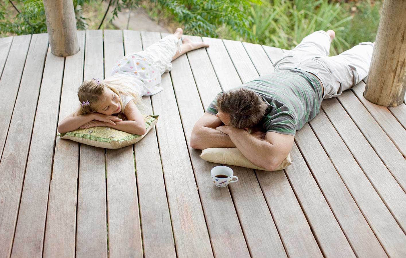 Vater und Tochter liegen auf Holzterrasse